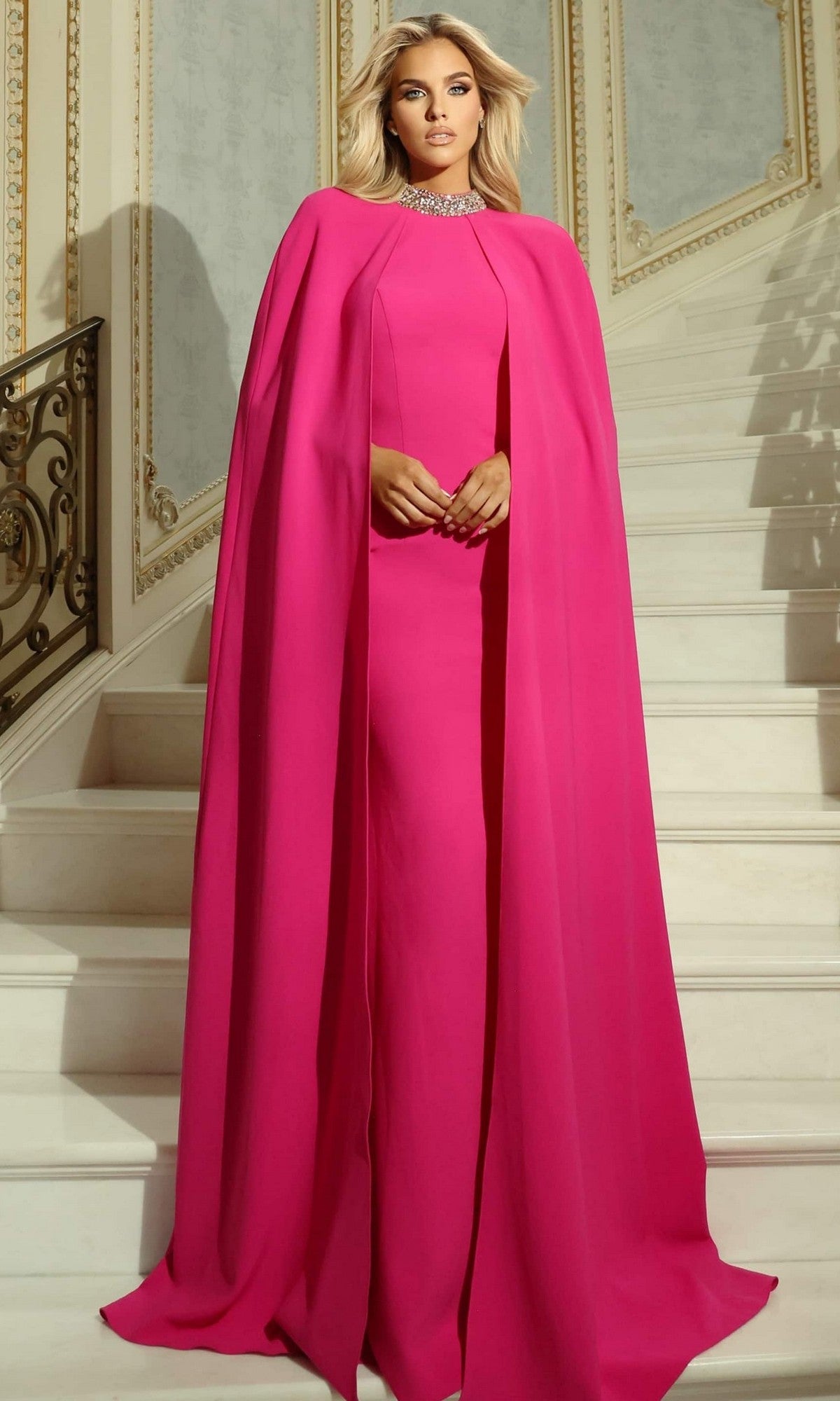 A woman in the Jovani 46736 long prom dress, featuring pink crepe fabric, a cape, and a crystal-embellished collar.